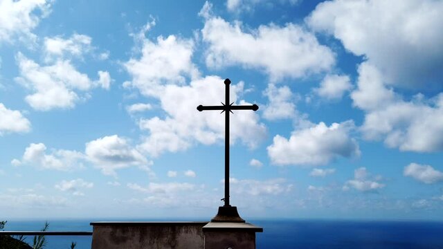 Time lapse of  Catholic cross of the Christian religion overlooking the sea and moving blue sky clouds