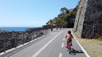 Italy, Spezia, Liguria - The new pedestrian walk , cycle path ( bicycle lane ) that connects Framura, Bonassola and Levanto passing through the ancient train tunnels - 7 years old child go bike
