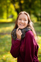 Happy smiling woman holding in her hands yellow maple leaves over autumn background