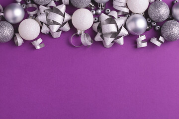 Holiday background with grey and white metallic decorations on purple. Copy space. Christmas and New Year.