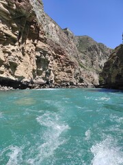 Fototapeta na wymiar deep canyon with a blue river and beautiful mountains against the sky