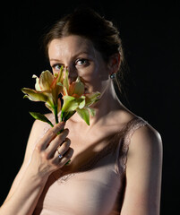 close-up portrait of a woman with a large flower on a black background