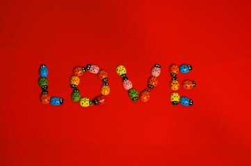 The word love consists of figures of ladybugs on a red background.