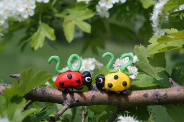 Figurines of two ladybirds made of plasticine. At the top is the calendar date 2022.
