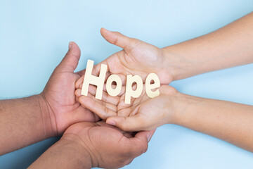 two hands holding word hope, prostate cancer, light blue background