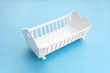 White baby crib isolated on blue background. Child birth rate concept