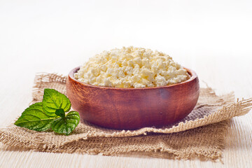 Bowl with cottage cheese on white wooden background