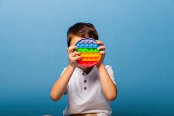 The boy holds clapping toys in his hands. Push game. Happy boy with pop it.