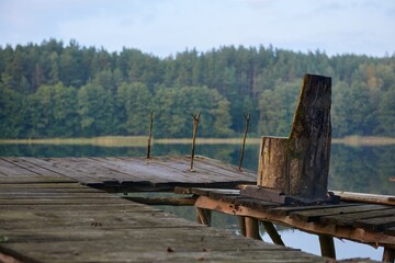 Opuszczone stanowisko wędkarskie nad jeziorem. Fotel wyciosany z pnia drzewa i widełki, podpórki na wędki - obrazy, fototapety, plakaty