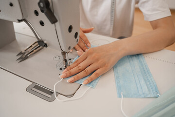 Cropped view of blurred seamstress sewing medical mask in atelier
