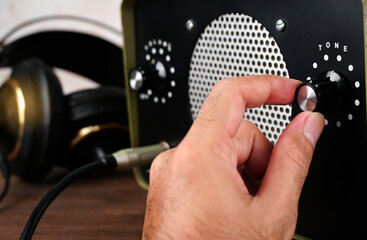 Hand adjusting volume tone control. Use hand to adjust the volume tone at the volume control button of the amplifier.	
