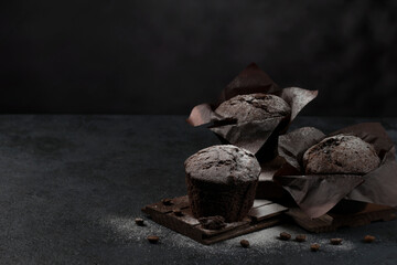 Chocolate coffee delicious muffins with powdered sugar on a dark background. Copy space. Selective focus. Low key.