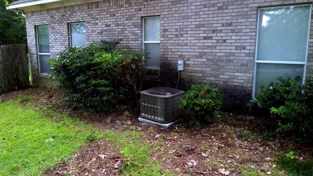 Old rusted Home HVAC Unit next to brick home.