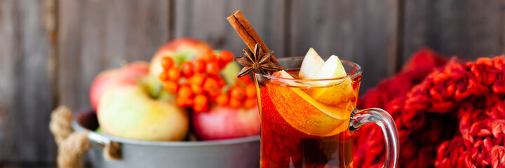 Homemade hot fruit tea with fresh apples, honey, spices: cinnamon, cardamon, anise, clove. Warm autumn drink, delicious healthy beverage. Mulled wine. Cozy home atmosphere. Wooden background, banner