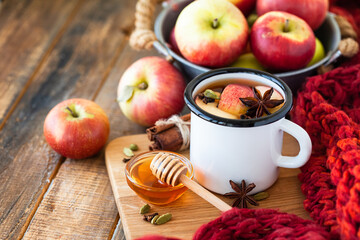Homemade hot fruit tea with fresh apples, honey, spices: cinnamon, cardamon, anise, clove. Warm autumn drink, delicious healthy beverage. Mulled wine. Cozy fall home atmosphere. Wooden background
