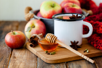 Homemade hot fruit tea with fresh apples, honey, spices: cinnamon, cardamon, anise, clove. Warm autumn drink, delicious healthy beverage. Mulled wine. Cozy fall home atmosphere. Wooden background