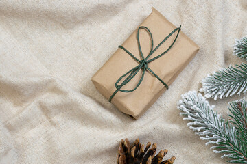 Zero Waste Christmas concept. Gift box in reusable paper and natural festive decorations on lien cloth background. Eco friendly plastic free holidays concept.