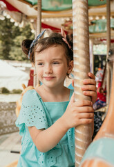 portrait of a little girl in a blue dress riding on an amusement park ride