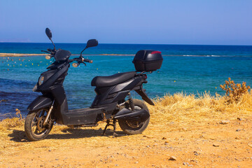 Black scooter by the sea