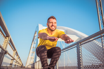 man wearing yellow t-shirt doing squats and smiling