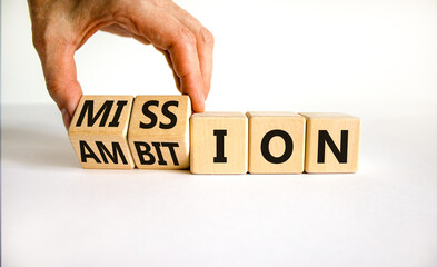 Do your mission with ambition. Businessman turns wooden cubes and changes the word 'mission' to 'ambition'. Beautiful white table, white background, copy space. Business, mission or ambition concept.