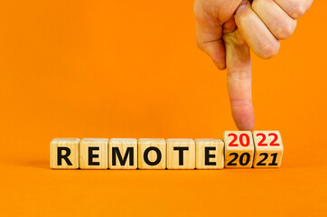 Planning 2022 remote new year symbol. Businessman turns wooden cubes and changes words 'remote 2021' to 'remote 2022'. Beautiful orange background, copy space. Business, 2022 remote new year concept.