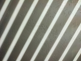 Blinds shade on a light textured wall.