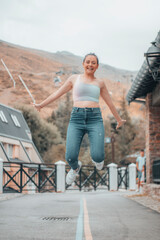 Chica joven saltando con felicidad en un pueblo rústico de la montaña