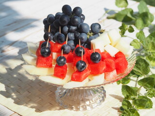 Canapes of grapes, pieces of watermelon and melon on a natural green background.