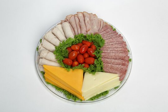 Closeup of party food platter with cheeses, deli meats, and cherry tomatoes