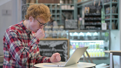 Redhead Young Man with Laptop in Cafe Coughing
