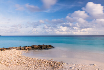 Long exposure water of Indian ocean with stones on the Maldivian island. Sunset time. Crossroads Maldives, july 2021