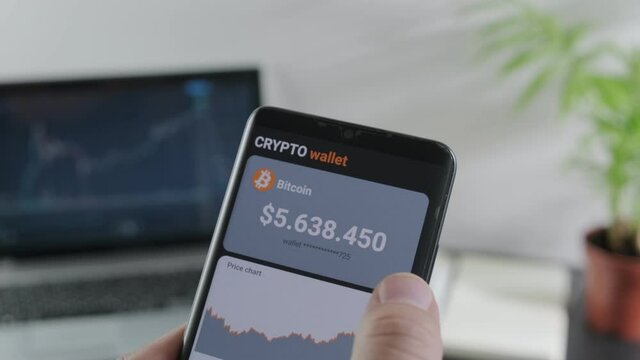 The man analyzes the price of bitcoin and buys bitcoin in the mobile application of the smartphone. Smartphone with mobile  application wallet cryptocurrency. The concept of cryptocurrency trading