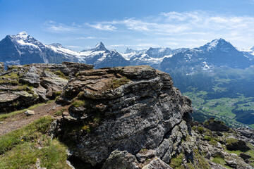 un promontoire rocheux devant une chaine montagneuse aux sommets enneigés