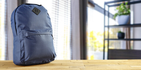 School backpack on wooden desk and window backgorund 