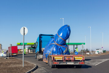 Blue truck with special semi-trailer for oversized loads transportation. Oversize load on flatbed trailer