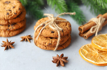Ginger Christmas cookies with chocolate chips on a gray background among the Christmas tree branches. Christmas pastries.