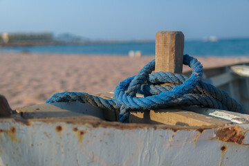 Blue rope on old boat to the shore of the sea.