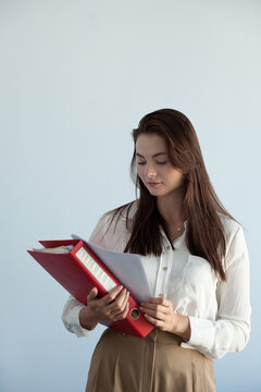 young beautiful girl in office clothes holds a folder and sheets of documents in her hands