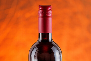 Garrafa de vinho tinto. Com lacre vermelho e fundo amarelado.