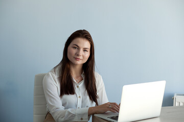 young beautiful girl in office clothes works on a laptop