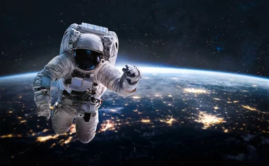 Deurstickers Astronaut in de kosmische ruimte op de baan van de planeet Aarde. Donkere ruimte en ruimtevaarder. Aarde & 39 s nachts. Elementen van deze afbeelding geleverd door NASA © dimazel