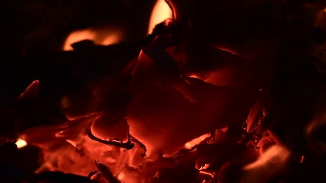 Close-up of a burning campfire, night bonfire, logs, plywood and fabric are on fire, a gust of wind blows up sparks, slo-mo HD video
