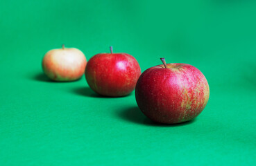 three red ripe apples on a green background