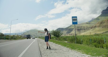 Russia, Caucasus. A woman catches a ride, standing on the side of the road