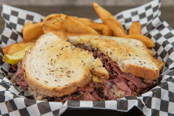 Pastrami sandwich with corned beef on grilled rye bread served with steak french fries for an appetizing meal