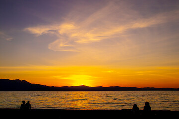 Beautiful sunset over Lake Tahoe CA USA with sihlouttes of two couples on beach watching