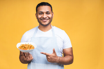 Portrait of of happy african american indian black man chef cooking pasta. Cooking, profession, haute cuisine, food and people concept isolated over yellow background.