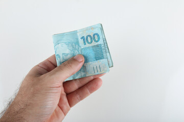Hand holding Brazilian money. 100 reais banknotes. copy space