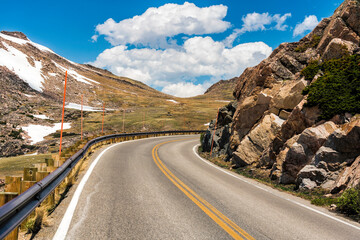 Asphalt winding road surrounded by rocks with snow in high Wyoming mountain